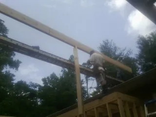Carpenter setting a ridge beam over a new addition frame — Ice Dam Removal by Roofing Brothers in Sanford