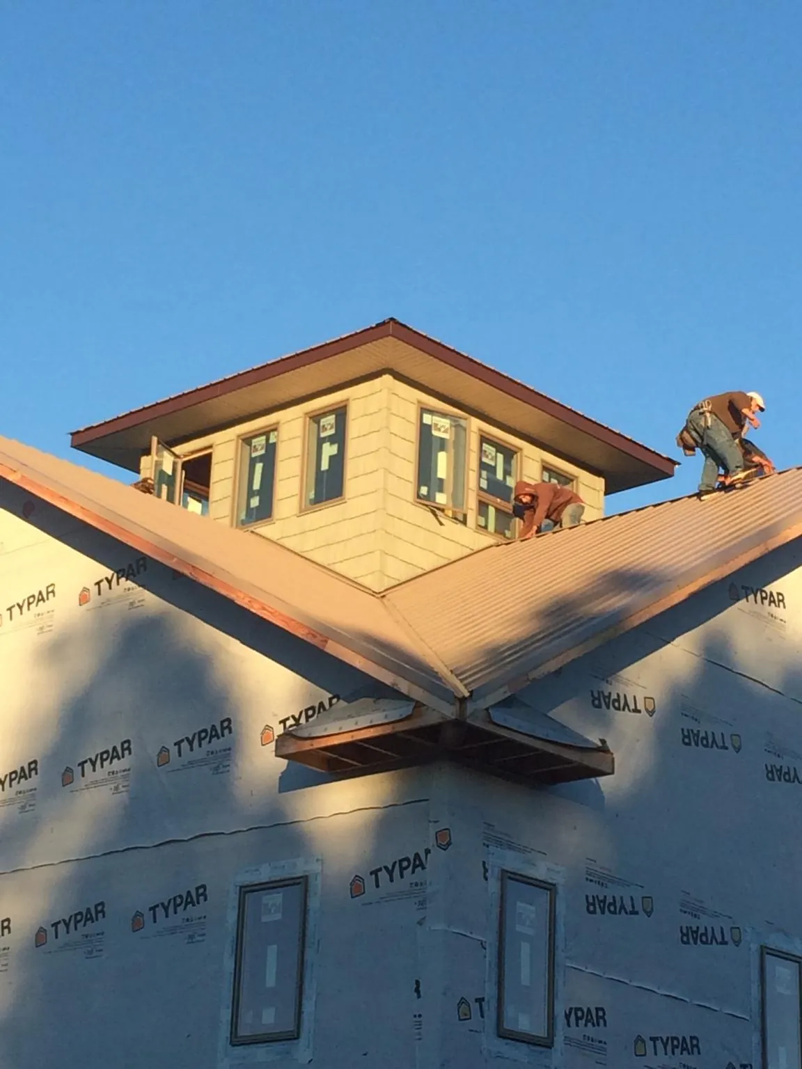 Roofers working around a rooftop cupola on a new metal roof at sunset — Roof Waterproofing in Sanford by Roofing Brothers